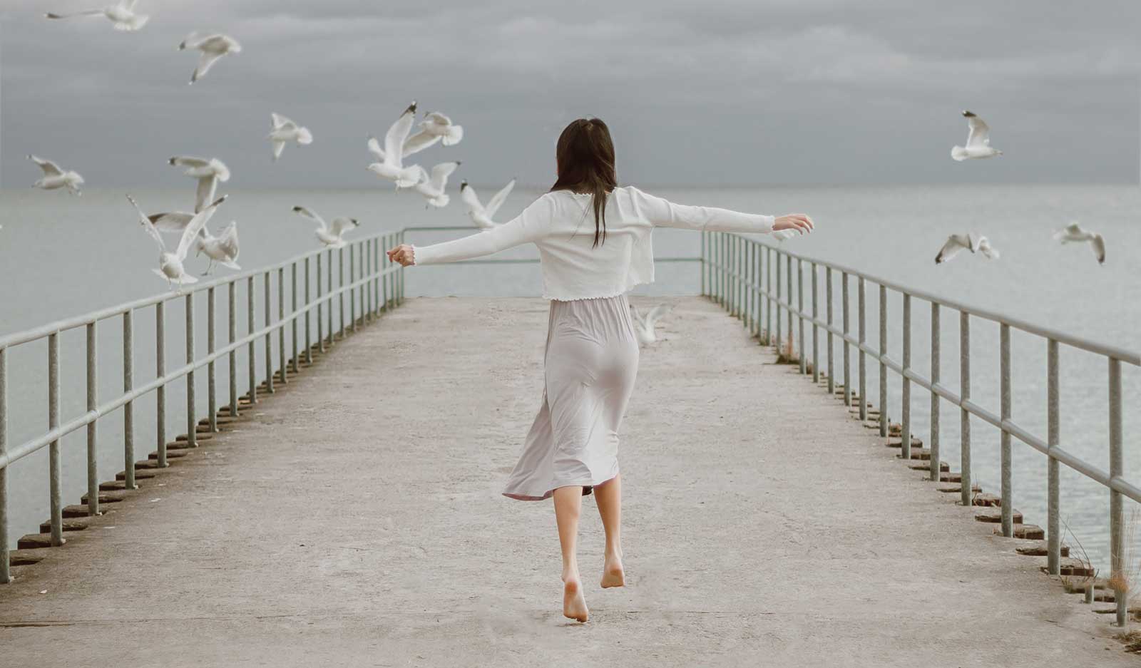 girl on dock with birds flying