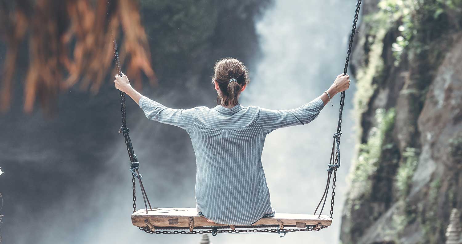 woman on a swing over a waterfall