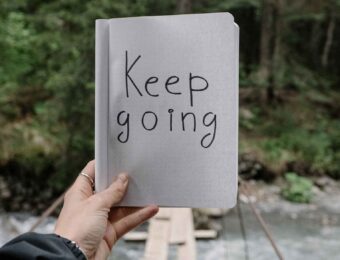 hand holding a sign that says keep going