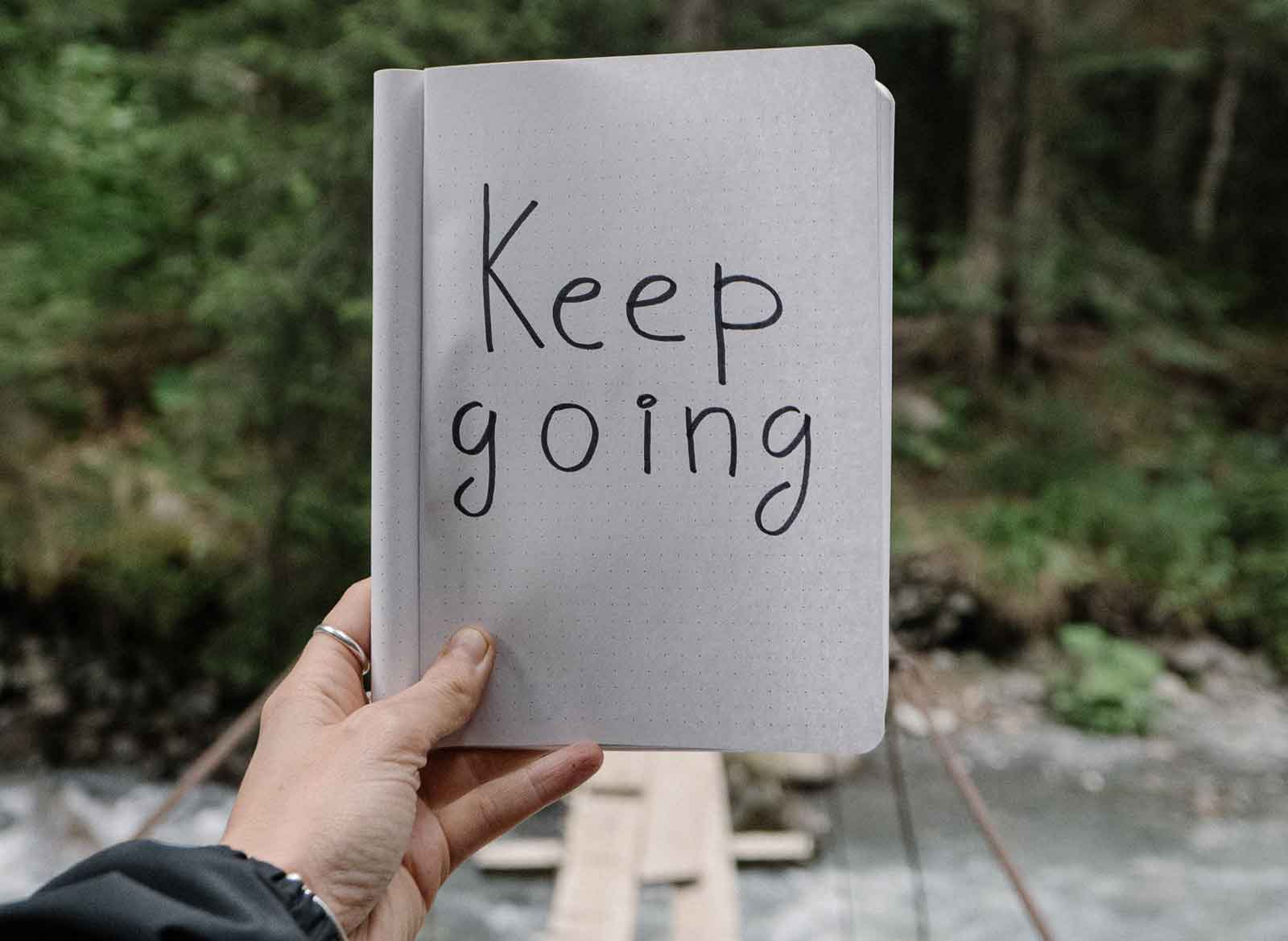 hand holding a sign that says keep going
