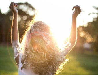 Girl in sunshine with hands up