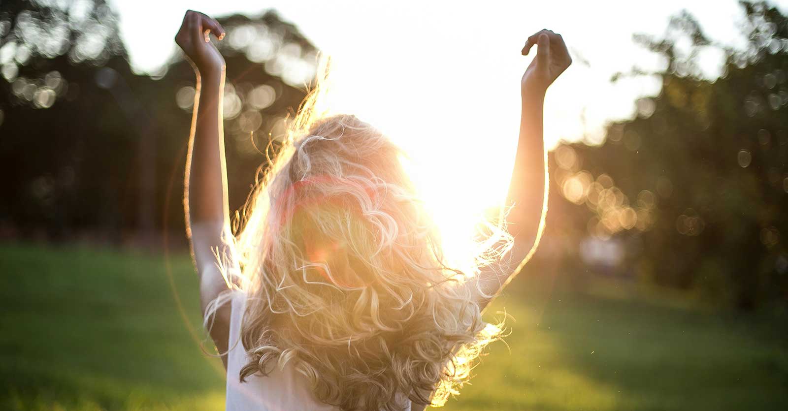 Girl in sunshine with hands up
