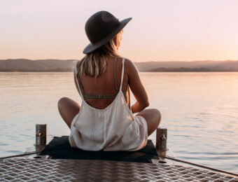 girl sitting by lake looking at sunset