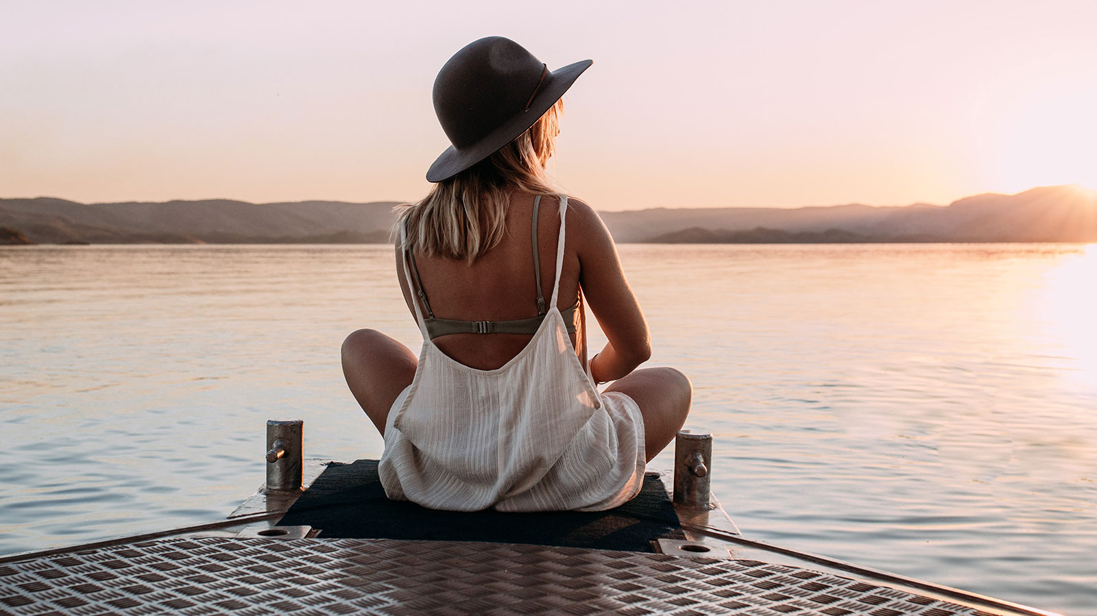 girl sitting by lake looking at sunset